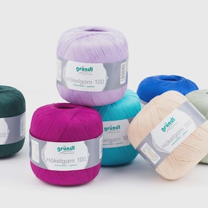 Könnte beinhalten: Eine Sammlung bunter Garnknäuel in Grün, Lila, Pink, Blau und Beige. Jedes Knäuel hat ein Etikett mit dem Text "gründl Häkelgarn 100". Das Garn ist auf einer weißen Oberfläche angeordnet.