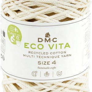 Peut inclure: Un écheveau de fil de coton recyclé de couleur naturelle, DMC Eco Vita, taille 4, pour des créations durables. L'étiquette indique "Seed Paper Label, Plant It!" et "Sustainable Crafts".