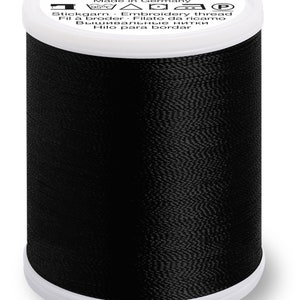 Puede incluir: Una bobina de hilo de bordar negro con el nombre de la marca "Polyneon Madeira" y el texto "Hecho en Alemania" en la etiqueta.