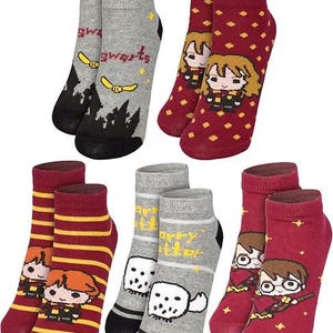 Puede incluir: Un conjunto de cinco pares de calcetines tobilleros con varios diseños. Un par es gris con la silueta del castillo de Hogwarts y una snitch dorada. Otro es granate con un patrón de rombos y un personaje. Otros presentan rayas, una lechuza blanca y un personaje sobre una escoba.