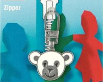 May include: A silver zipper pull with a white teddy bear charm. The zipper pull is attached to a zipper with a green and blue background. The image also includes the text "Prym Zipper" and the product number "482 173".