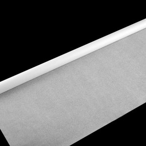 Puede incluir: Un rollo de papel pergamino blanco, desenrollado sobre un fondo negro.