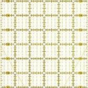 Puede incluir: Una regla Omnigrid blanca con un patrón de cuadrícula en dorado. La regla mide 15,2 cm por 61 cm.