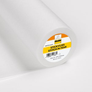 Puede incluir: Un rollo de entretela fusible blanca Vlieseline Stitch-N-Tear. La etiqueta es amarilla con texto negro y dice "STICKVLIES STITCH-N-TEAR 70% CV, 30% Celulosa 90 cm x 25 m".