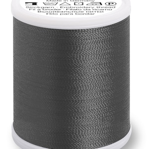 Puede incluir: Una bobina de hilo de bordar gris oscuro con la etiqueta "Polyneon Madeira" y el texto "Made in Germany" y otros idiomas.