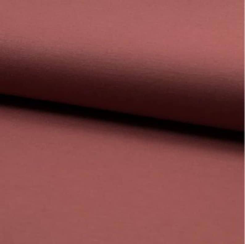 May include: A close-up of a solid, deep red fabric. The fabric has a smooth, slightly textured surface.