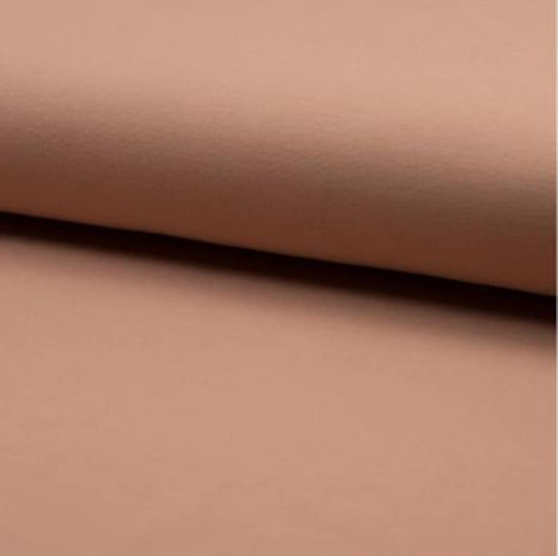 May include: A close-up of a soft, peach-colored fabric with a subtle textured surface.