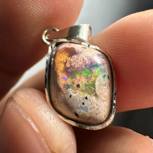 May include: A silver pendant with a pink, white, and green opal stone. The stone has a rough, natural texture and is set in a silver bezel.