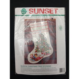 May include: A Sunset brand counted cross stitch kit for a Musical Christmas Tree Stocking. The package features a white stocking design with a decorated Christmas tree, musical notes, and the name Elizabeth. Finished size is 16 inches long.