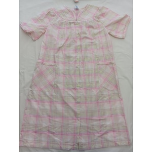 May include: A light pink and white plaid robe with short sleeves and two front pockets. The robe has a button-up front and a decorative collar. The plaid pattern includes light green and pink lines. The robe is made of a lightweight fabric.