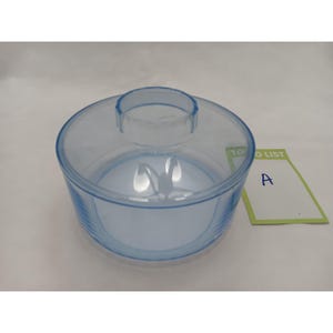 May include: A round, transparent light blue plastic container lid with a central circular handle. Next to the lid is a small rectangular green and white card with the text TO DO LIST and the letter A written in blue ink on the white section.