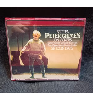 May include: A CD case featuring the opera "Peter Grimes" by Benjamin Britten, starring Jon Vickers. The cover art shows a man in a sweater and boots, with text including the names of the performers and the Royal Opera House.