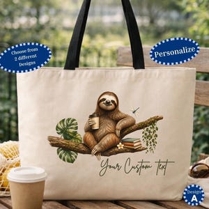 May include: A beige canvas tote bag with black handles featuring a graphic of a brown sloth sitting on a tree branch holding a coffee cup, next to a stack of books, a dragonfly, and green leaves, with the text Your Custom Text printed below.