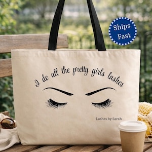 May include: A beige canvas tote bag with black handles featuring a black graphic of closed eyes with long eyelashes. The text reads I do all the pretty girls lashes and Lashes by Sarah in a black script font centered on the front of the bag.