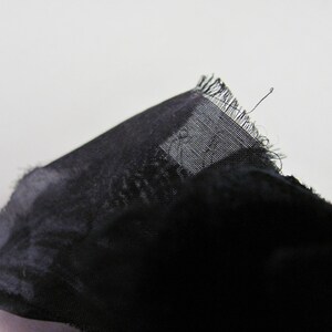 May include: Black sheer fabric with a frayed edge.