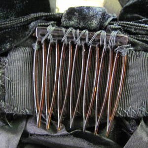 May include: A close-up of a brown comb with black velvet fabric and black ribbon behind it.