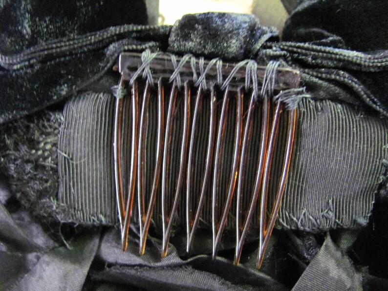 May include: A close-up of a brown comb with black velvet fabric and black ribbon behind it.