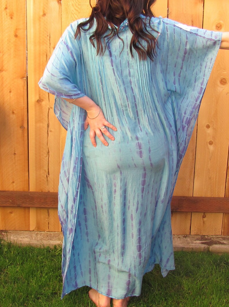 May include: A long, flowing blue and purple tie-dye kaftan dress. The dress has a loose, comfortable fit and is perfect for a casual summer look.