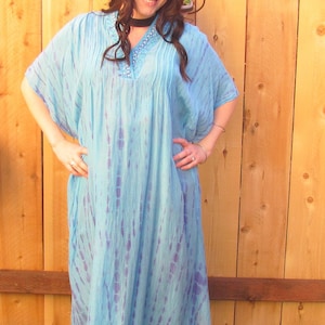 May include: A long, flowing blue and purple tie-dye dress with a beaded neckline. The dress has a relaxed fit and is perfect for a casual summer look.