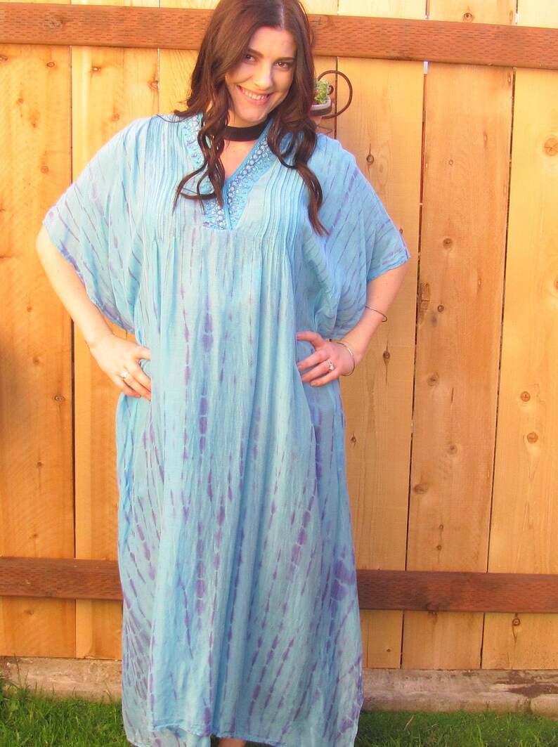 May include: A long, flowing blue and purple tie-dye dress with a beaded neckline. The dress has a relaxed fit and is perfect for a casual summer look.