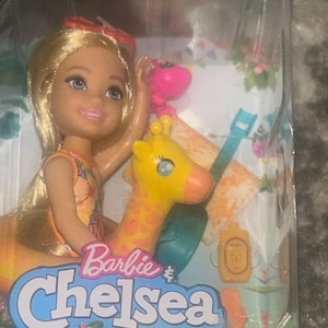 以下が含まれることがあります： 黄色とオレンジの浮き輪と黄色のキリンのフロートに乗ったバービーチェルシー人形。パッケージには「バービー＆チェルシー ザ・ロスト・バースデー」の文字とマテルのロゴが記載されています。