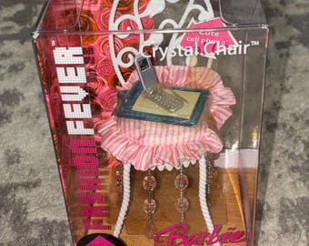 May include: A Barbie Crystal Chair set in a clear plastic box. The chair has a white frame, pink and white striped seat, and dangling pink beads. A miniature cell phone sits on a small table. The box reads "Room Fever".