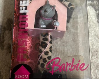 May include: A Barbie "Kitty Corner" playset in a clear plastic box. The set includes a pink cat house with a gray cat figure, a leopard print pole, and the Barbie logo. The box also has the text "Room Fever".