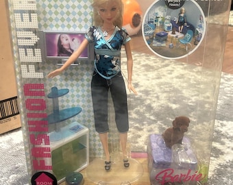 May include: Barbie Fashion Fever doll with a blue and black outfit, a brown dog, and a blue and white entertainment center. The box says "Create the perfect room!" and "Barbie".