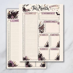 Printable monthly planner pages with a gothic spooky-cute design, featuring black cats, bats, roses, moons, crystals, butterflies, and floral accents. Includes sections for tasks, top priorities, monthly goals, events, reminders, notes, and memories. Two planner pages shown on a light grey background.