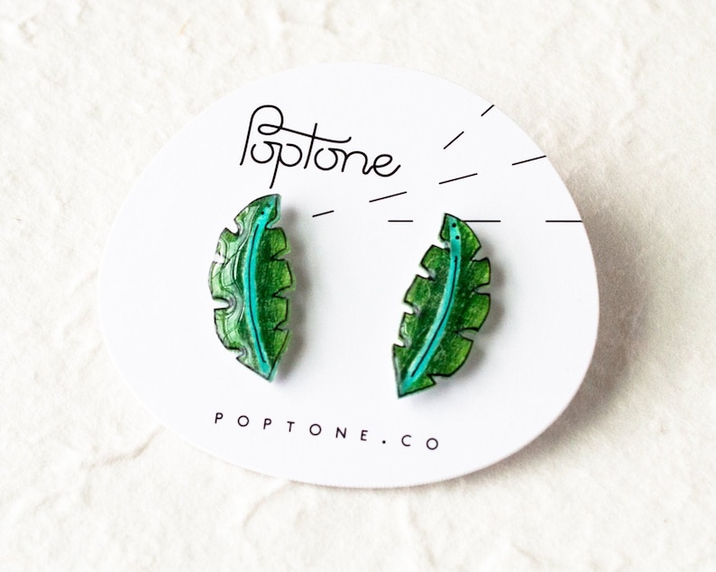 May include: A pair of green and blue leaf-shaped earrings on a white card with the text "Poptone.co".