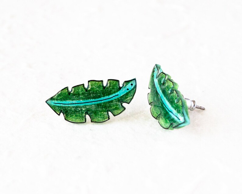 May include: A pair of green leaf-shaped earrings with a blue line down the center. The earrings are made of resin and have a post back.
