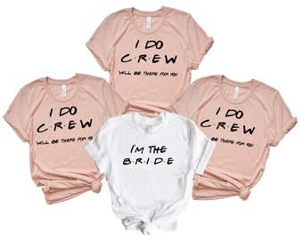 Peut inclure: Quatre t-shirts roses avec le texte "I DO CREW WILL BE THERE FOR YOU" et un t-shirt blanc avec le texte "I'M THE BRIDE".