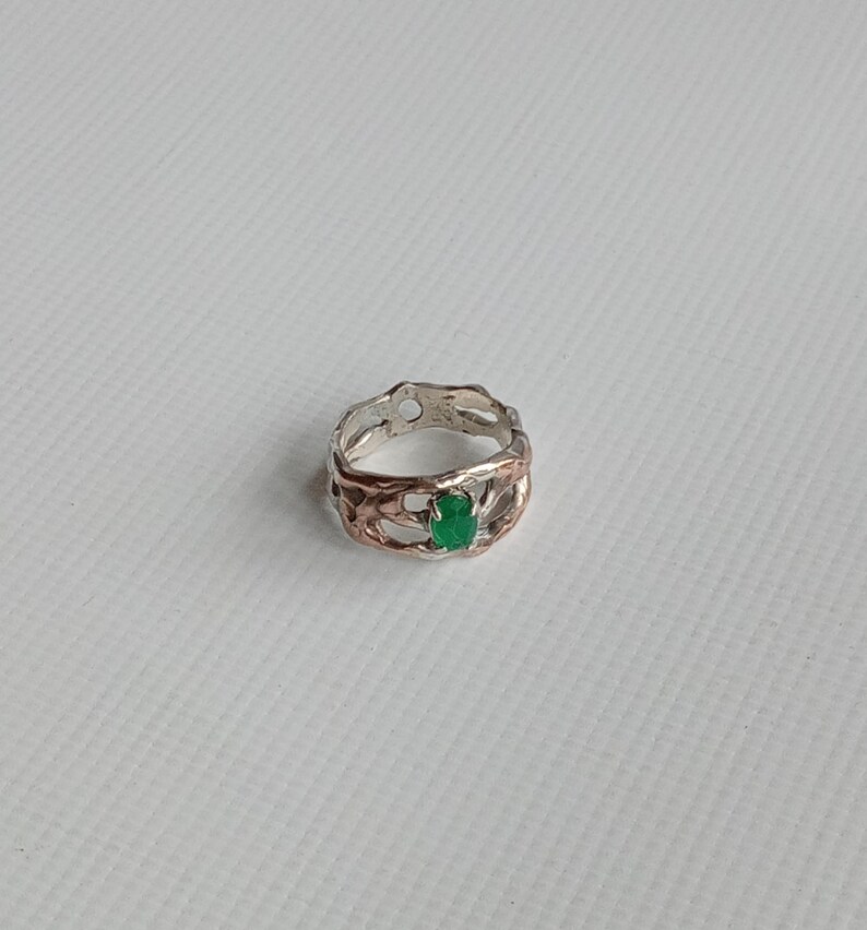 May include: A silver ring with a green gemstone set in a delicate, intricate design.