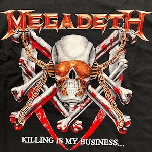 May include: Black t-shirt with a skull and crossbones graphic. The skull is wearing goggles and the bones are chained together. The text "MEGADETH" is at the top and "KILLING IS MY BUSINESS..." is at the bottom.