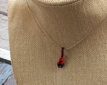 May include: A red and black wire wrapped pendant necklace on a burlap mannequin.