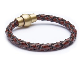 May include: A brown leather bracelet with a black braided design and a gold-toned magnetic clasp.