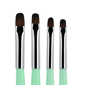 May include: Set of four makeup brushes with silver metal ferrules and mint green handles. The brushes have different sizes and are arranged in order of size from left to right.
