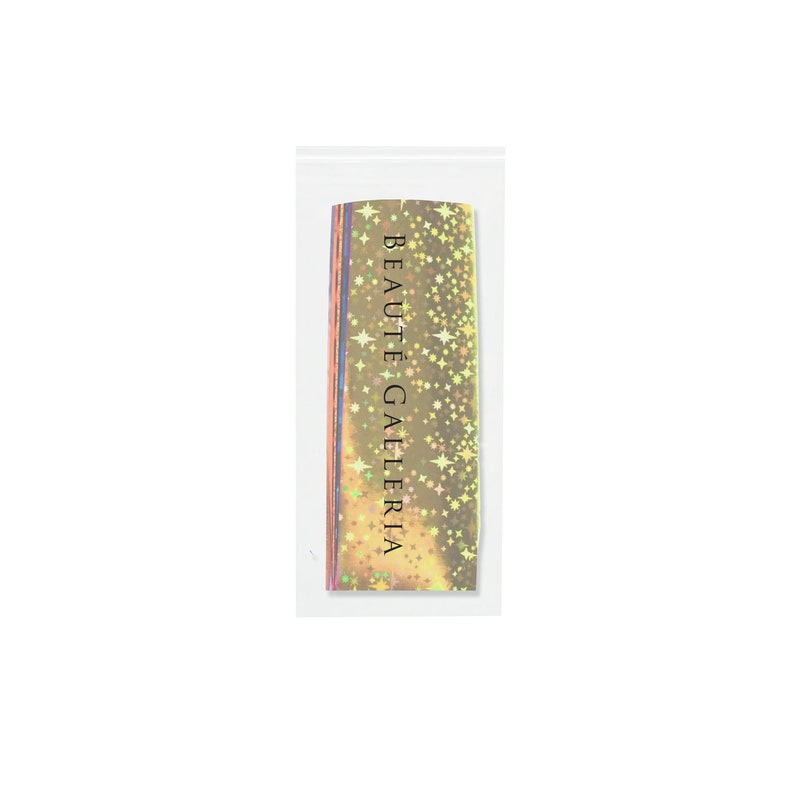 May include: A package of holographic nail tape with a gold background and a scattering of white stars. The package has the text "BEAUT&Eacute; GALLERIA" printed on it.