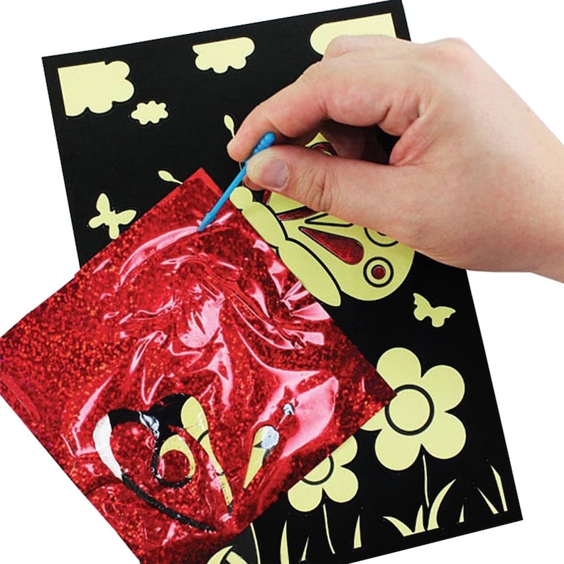 May include: A red glitter craft sheet with a butterfly design is being used to create a craft project on a black background with yellow butterfly and flower designs. A blue tool is being used to apply the glitter sheet to the black background.