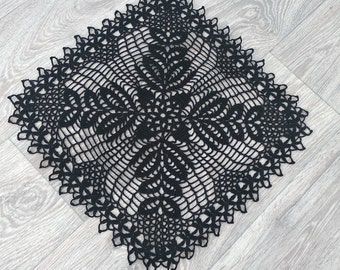May include: Black crochet doily with a floral design. The doily is square shaped and has a delicate lace pattern.