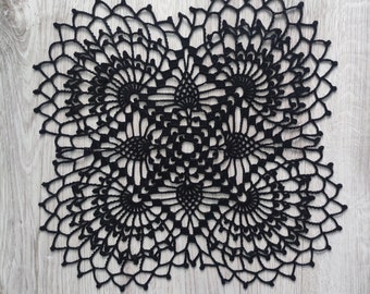 May include: Black crochet doily with a floral design. The doily is made of delicate, intricate stitches and has a circular shape.
