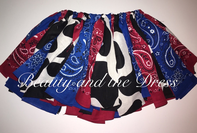 May include: A colorful skirt made from bandanas in red, white, and blue paisley patterns. The skirt is gathered at the waist and has a cow print bandana in the center.