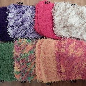 Puede incluir: Ocho cuadrados de ganchillo de diferentes colores, cada uno con una textura peluda. Los cuadrados están etiquetados con las letras SP y VP seguidas de un número.