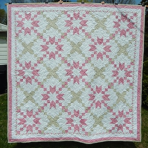 Peut inclure: Une courtepointe rose et blanche avec un motif d'étoiles. La courtepointe est suspendue à une corde à linge à l'extérieur.