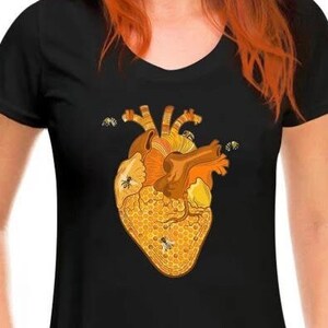 Puede incluir: Una camiseta negra con un gráfico de un corazón humano hecho de panal con abejas volando alrededor.