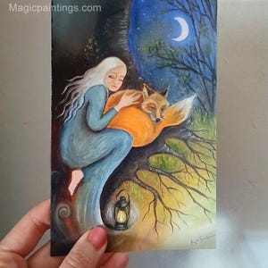 Könnte beinhalten: Gemälde einer Frau mit langen weißen Haaren in einem blauen Kleid, die einen schlafenden orangefarbenen Fuchs umarmt. Der Hintergrund zeigt eine Nachtszene mit einem Halbmond, Bäumen und einer Laterne. Die Website magicpaintings.com ist sichtbar.