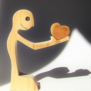 a man offers a heart; whipped wood sculpture