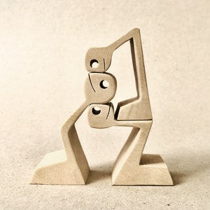 Può includere: Un paio di fermalibri in legno dal design minimalista. Ogni fermalibro presenta una base e una figura astratta con ritagli circolari. Il colore naturale del legno aggiunge un tono caldo e neutro all'arredamento.
