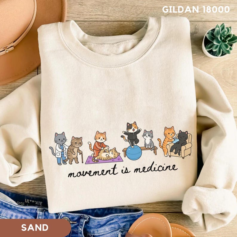 Cute physical therapy sweatshirt featuring cartoon cats demonstrating rehabilitation exercises with the phrase “Movement Is Medicine,” printed on a Comfort Colors® garment-dyed tee. pt week gift, rehab therapist shirt, outpatient therapy, pediatric physical therapist, dpt student gift, clinic staff shirt, therapy department gift, physical therapy, therapist gift, physical therapist, pt school shirt, rehab therapist, pt graduation, pt student gift, movement medicine, pediatric therapist