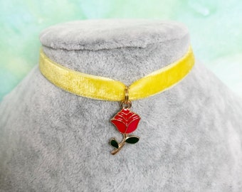 May include: A yellow velvet choker necklace with a gold-toned charm of a red rose.
